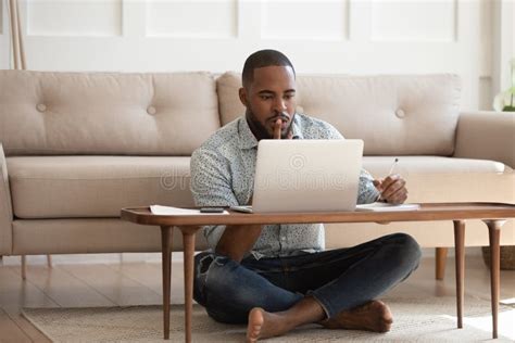 Focused African Man Studying Or Working On Laptop At Home Stock Image