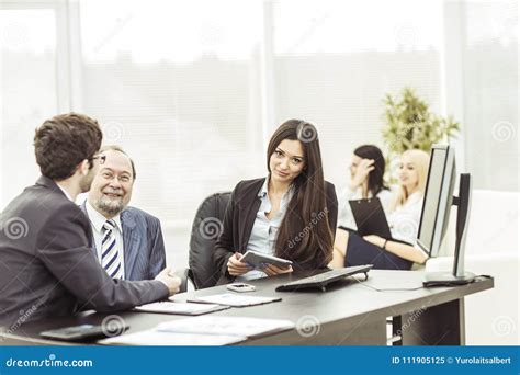 Boss And Members Of The Business Team Sitting At Workplace On