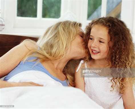 Mother Lying In Bed Kissing Daughter Smiling Photo Getty Images
