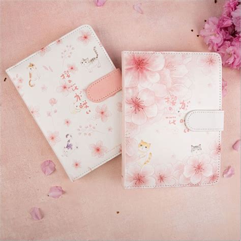 Two Notebooks Sitting Next To Each Other On A Pink Surface With Flowers