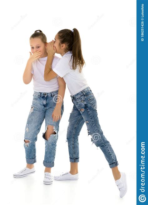 2 Ярких девочки делятся секретами в ухе друг друга Стоковое Фото изображение насчитывающей