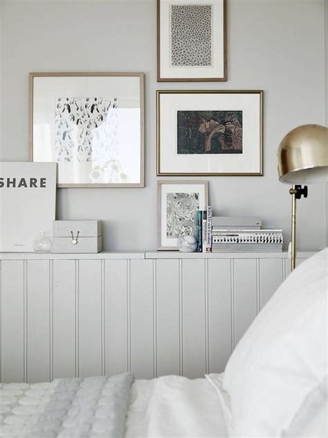 A Bed With White Sheets And Pictures On The Wall Above It Along With A