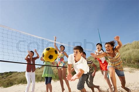 Group Of Teenage Friends Playing Volleyball On Beach Stock Photo