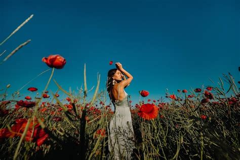 Retrato de una niña con un vestido en un campo de amapolas al atardecer Foto Premium