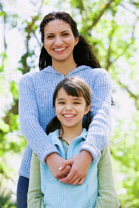 Hispanic Mother And Daughter Hugging Outdoors Stock Photo Dissolve