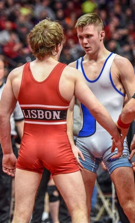 Two Men In Wrestling Uniforms Standing Next To Each Other