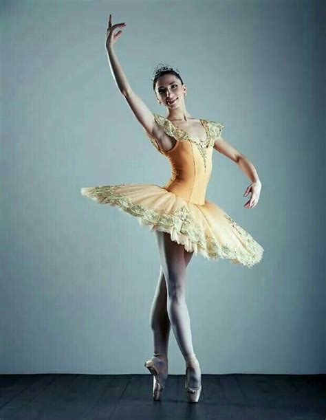A Ballerina In An Orange Tutu And Gold Dress Is Posing For The Camera