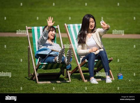 Two Women Enjoy Sun On Deckchairs In St James Park Hi Res Stock