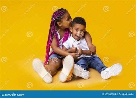 Adorable African American Siblings Sitting On Floor And Cuddling Stock