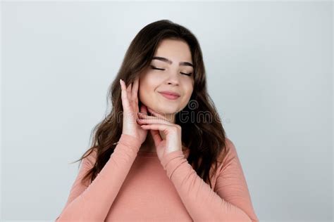 Young Beautiful Woman Touches Her Face With Both Hands Standing On