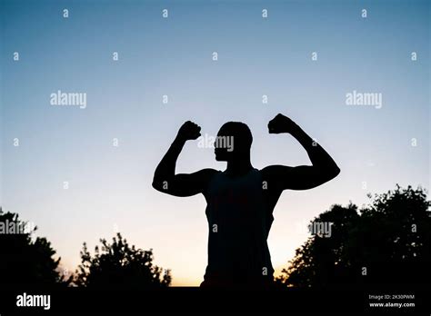 Silhouette Of Young Man Flexing Muscles At Sunset Stock Photo Alamy
