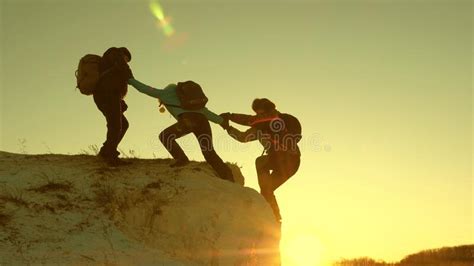 Team Of Climbers Climbs A Mountain Holding Out A Helping Hand To Each