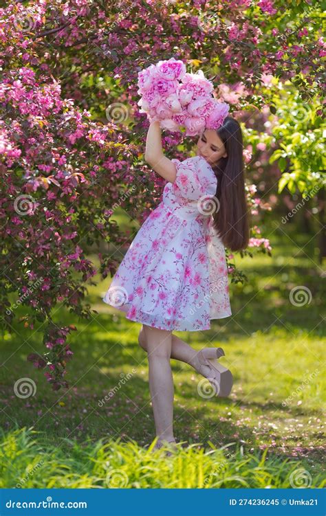 A Girl Dress With A Bouquet Of Large Pink Peonies Stand In Blossom
