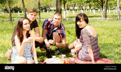 College Friends Having A Picnic In The Park With Two Attractive Couples