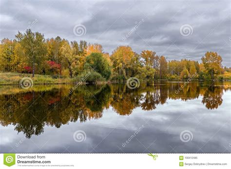 The Lake Reflecting The Cloudy Sky And Autumnal Foliage Trees Stock