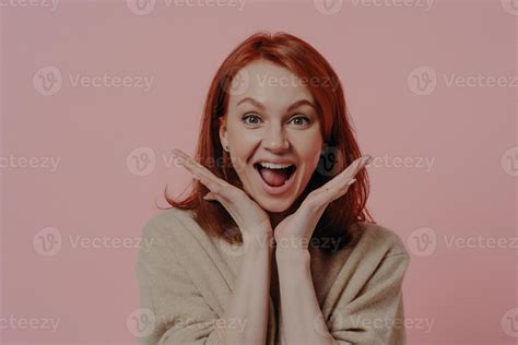 surprised beautiful ginger woman spreading palms near face and keeping mouth open from