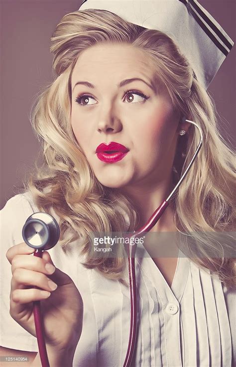 Portrait Of A Young Retro Nurse Holding Up Her Stethoscope Looking