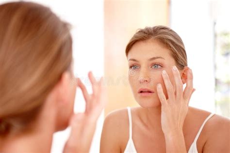 Taking Care Of Her Skin A Naturally Gorgeous Woman Applying Moisturizing Cream In A Mirror