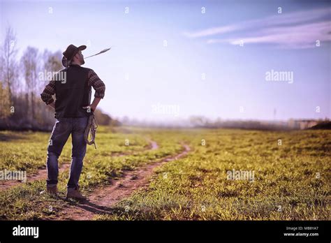 Cowboy Standing In A Field At Sunset Stock Photo Alamy