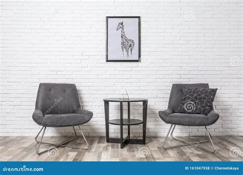 Room Interior With Modern Chairs And Table Near Brick Wall Stock Photo