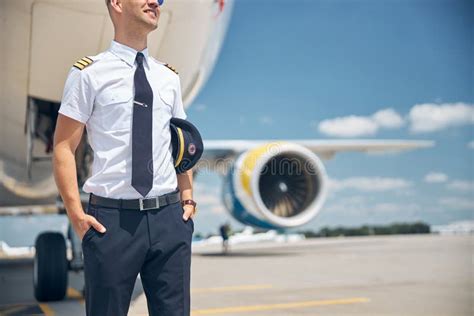 Cheerful Male Pilot Standing By The Plane At Airport Stock Photo