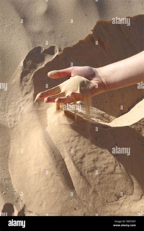 sand slipping through the fingers of a woman s hand in the desert of sahara in tunisia stock