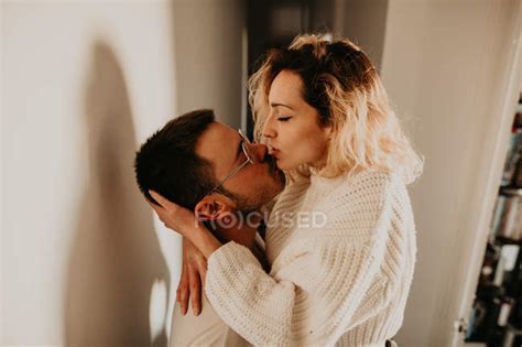 Passionate Couple Embracing And Kissing At Wall At Home Hall Side