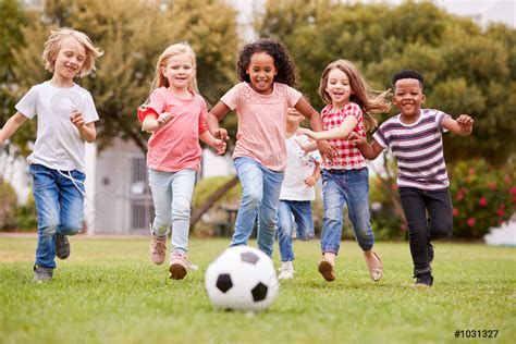 مجموعة من الأطفال يلعبون كرة القدم مع الأصدقاء في المنتزه صورة الأسهم