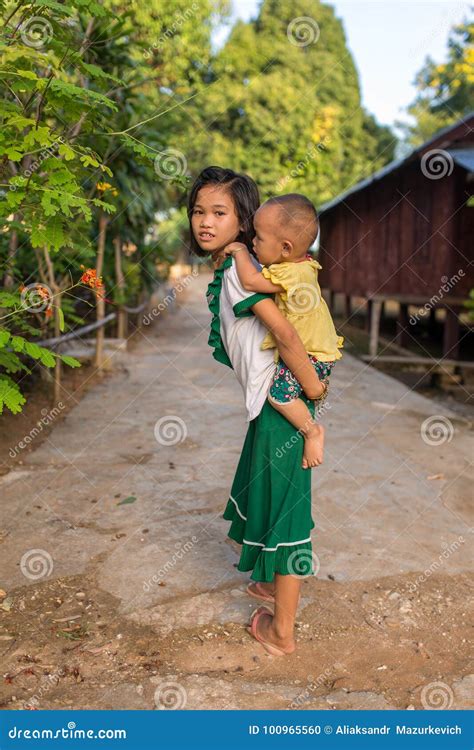 Cute Burmese Girl Carrying Small Boy In Rural Area In Burma Editorial