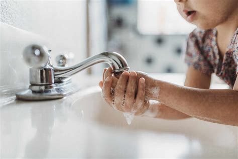 Close Up View Of Young Child Washing Hands With Soap In Sink Stock Photo