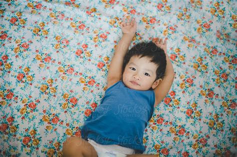 Baby Boy Lying On Floral Bedsheet By Stocksy Contributor Alita