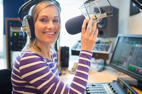 A Woman Wearing Headphones And Holding A Microphone In Front Of A