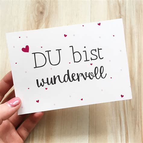 Someone Holding Up A Card With The Words Du Bis Wundervele On It