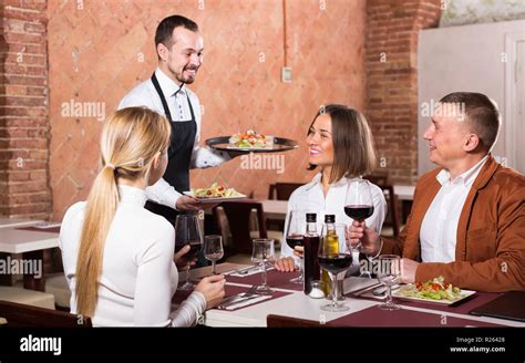 happy waiter placing order in front of guests in country restaurant Stock Photo: 225099008 - Alamy