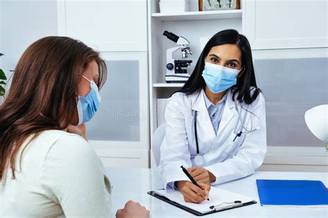 Doctor And Patient In Face Masks Discussing Health Problems While