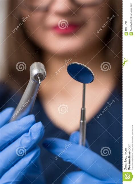 Dentist With Blue Gloves Holding Dental Equipment Drill And Mirror At