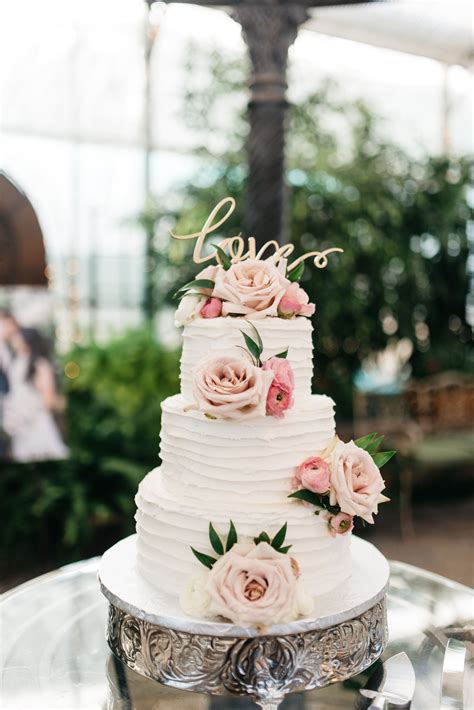 3 tier white wedding cake with fresh pink roses