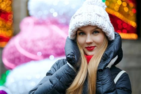 Premium Photo Charming Blonde Woman Wearing Knitted Cap Posing At The Street Over A Garlands