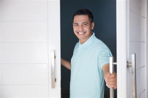 hombre abre la puerta de su casa y sonriendo foto premium