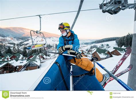 Skier Guy Sitting At Ski Chair Lift In Beautiful Day And Turns Back