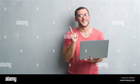 los jóvenes caucásicos hombre sobre gris pared grunge utilizando el ordenador portátil