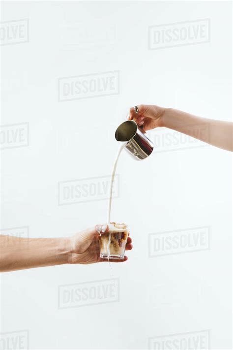 Cropped View Of Hand Pouring Milk Into Glass With Coffee Isolated On