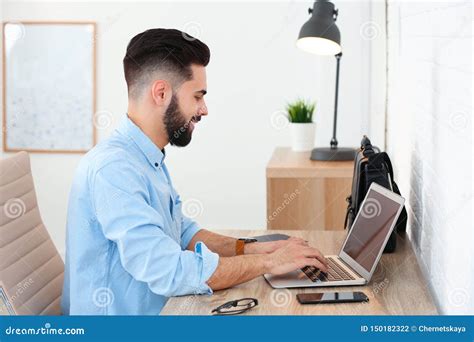 Handsome Young Man Working With Laptop At Table In Home Stock Photo