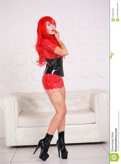 Kinky Redhead Woman Posing In Red Latex Dress And Black Rubber Corset