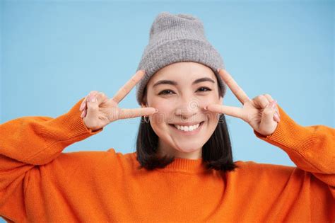 Close Up Portrait Of Cute Korean Girl In Beanie Shows Peace Vsign