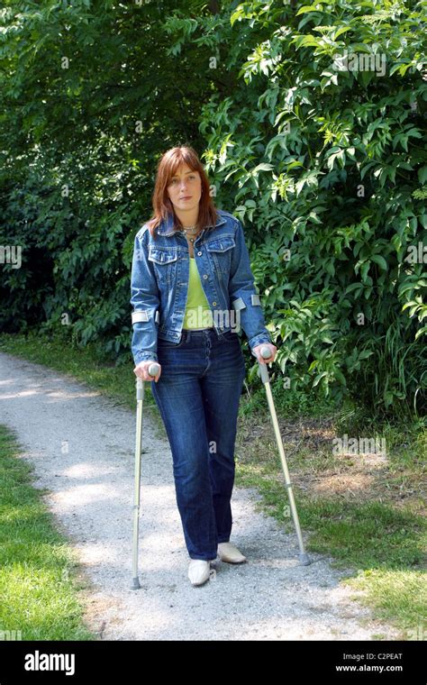 Woman Walk On Crutches In Park Stock Photo Alamy