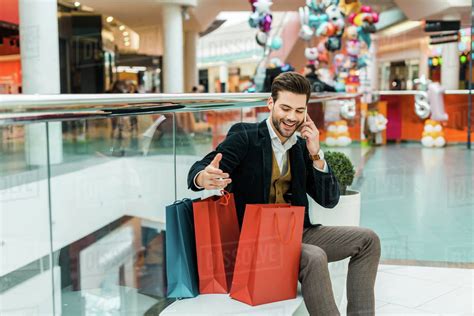 Handsome fashionable man with shopping bags talking on smartphone while ...