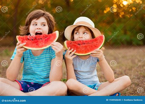 Funny Happy Children Eating Watermelon In Park At Sunset Stock Photo