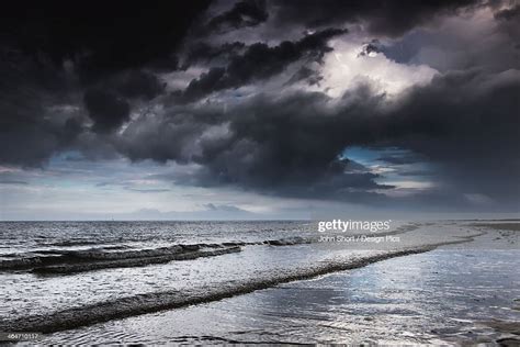 Dark Storm Clouds Over The Ocean With Waves Rolling Into The Shore High