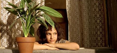 A Woman Sitting Next To A Potted Plant On Top Of A Window Sill